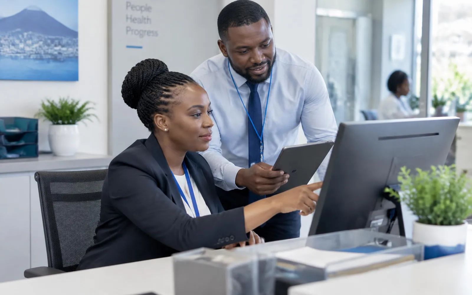Healthcare administrative staff coordinating appointment schedules on a desktop and tablet in a modern hospital office.